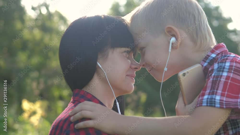 happy family funny video lifestyle slow motion play music teamwork outdoors. Mom and son listen to music on smartphone in same headphones for two. happy family mother woman and little boy son spend happy family funny video lifestyle slow motion play music teamwork outdoors. Mom and son listen to music on smartphone in same headphones for two. happy family mother woman and little boy son spend