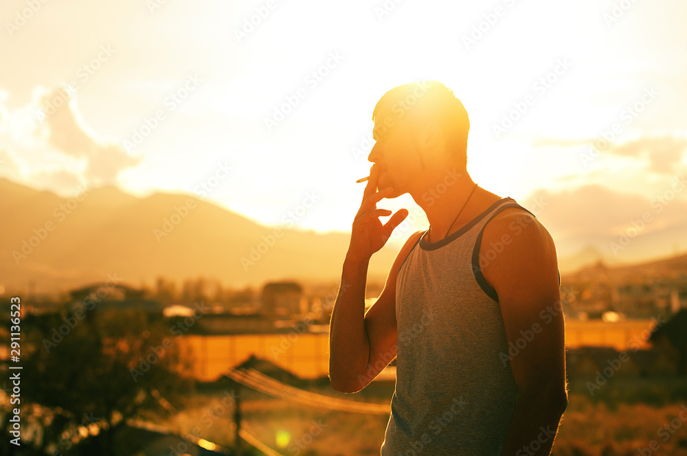 A silhouette of a man smoking a cigarette and standing on the hill A silhouette of a man smoking a cigarette and standing on the hill