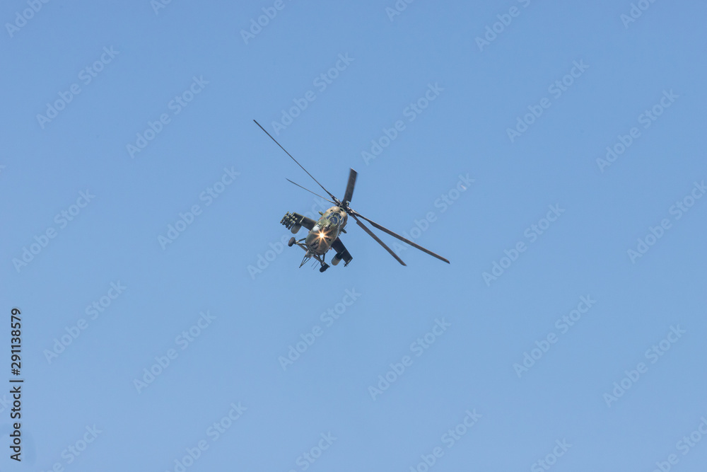 Fototapeta premium A green military helicopter flying towards the camera - clear blue sky