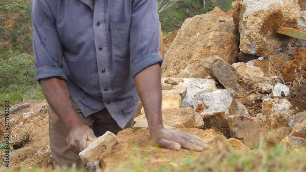 Side view of unrecognizable indian man cutting a block of granite with