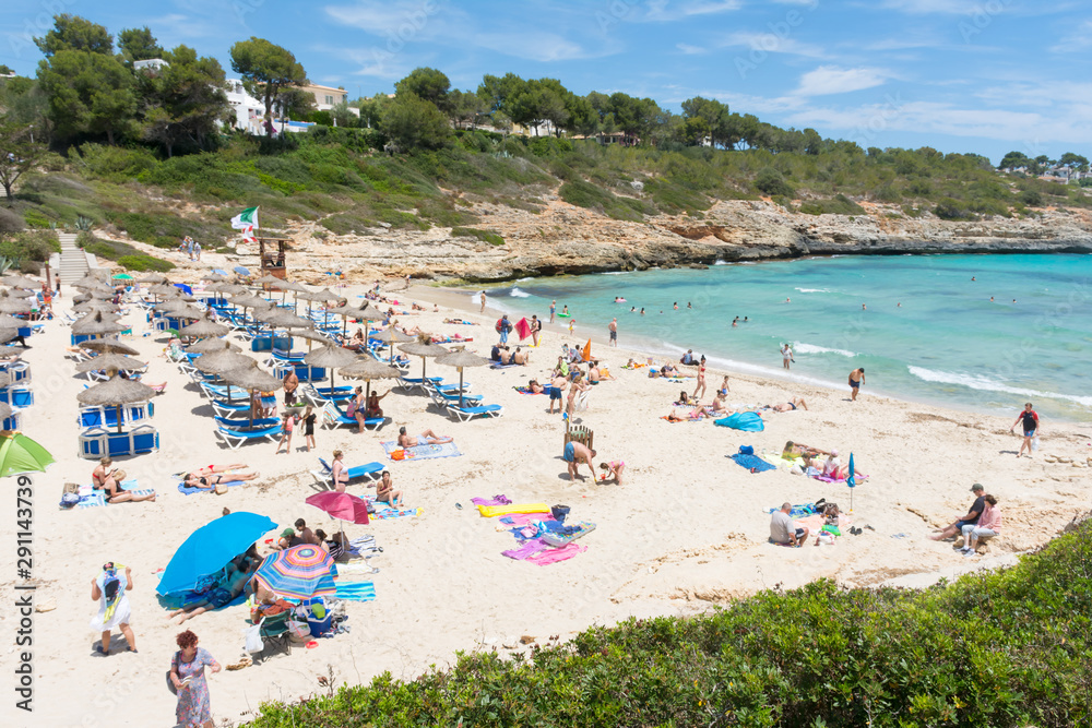 People relax on the beach in Cala Mandia Bay