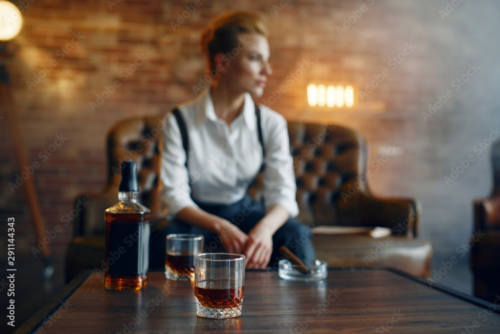 Woman in shirt and trousers with whiskey and cigar