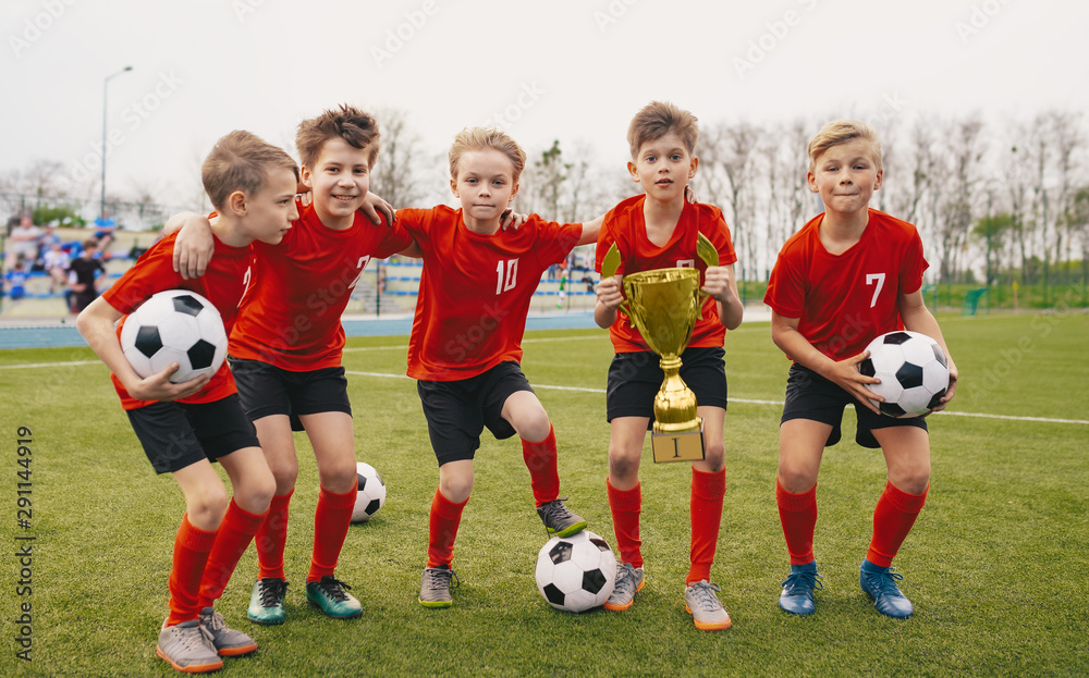 Happy Junior Sports Team. Young Boys in Soccer Team Holding Golden Cup and Soccer Balls. Group of children Winning School Sports Tournament. Schools Football Championship for Kids Happy Junior Sports Team. Young Boys in Soccer Team Holding Golden Cup and Soccer Balls. Group of children Winning School Sports Tournament. Schools Football Championship for Kids