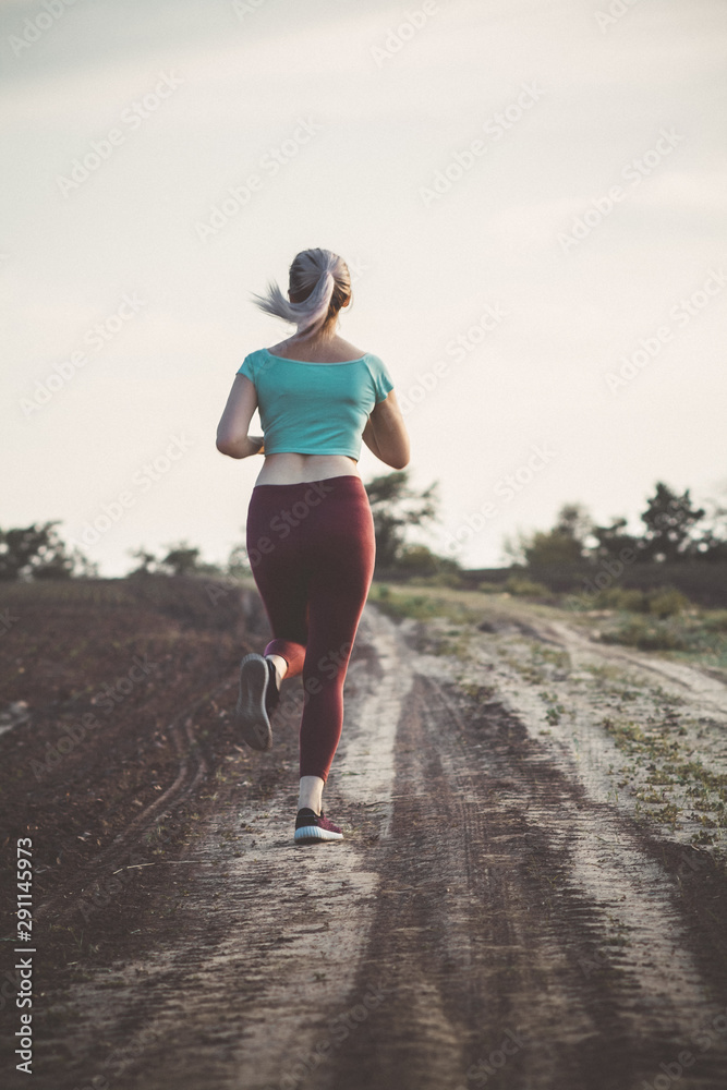 back of young woman in sportswear running distance in the field, girl engaged in sport outdoors, concept healthy lifestyle back of young woman in sportswear running distance in the field, girl engaged in sport outdoors, concept healthy lifestyle