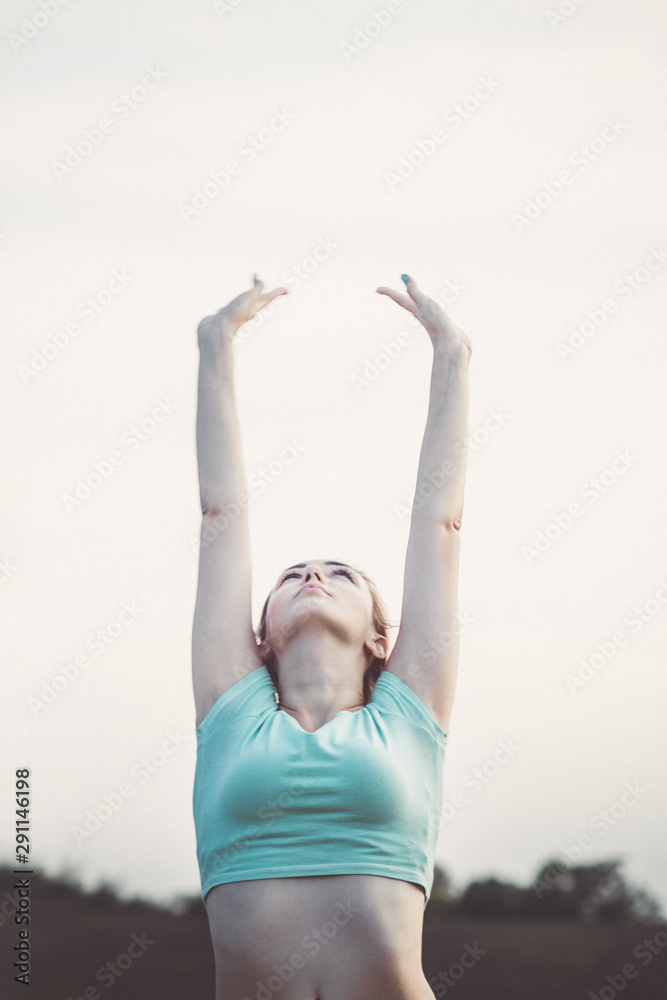 young woman doing breathing exercises in nature, taking a deep breath raising her head and arms up, girl is engaged in fitness outdoors, concept sport and healthy lifestyle young woman doing breathing exercises in nature, taking a deep breath raising her head and arms up, girl is engaged in fitness outdoors, concept sport and healthy lifestyle