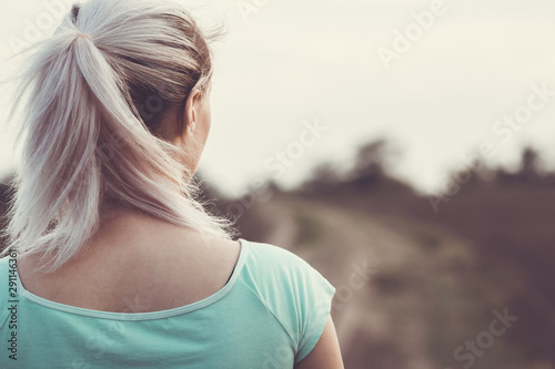back of female head on the background of the jogging track in the field, girl with ponytail for sports on nature