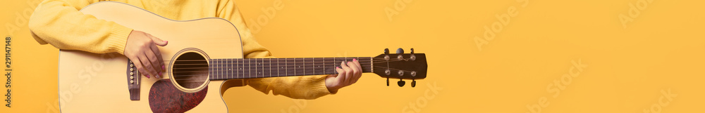 Fototapeta premium guitar in hands over yellow background, panoramic mock up image