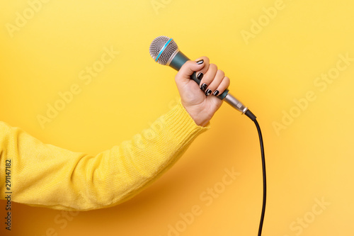 hand holding microphone over yellow background
