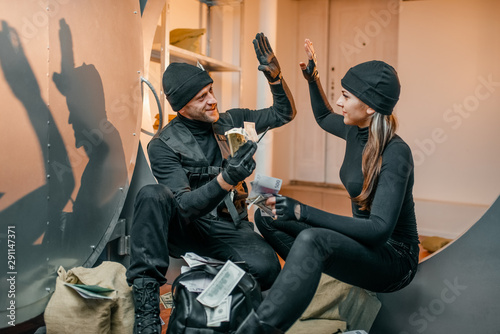 Foto Two robbers in black uniform stuff bags with money