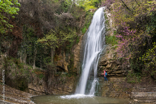 A girl stands next to a waterfall in the Tbilisi Botanical Garden