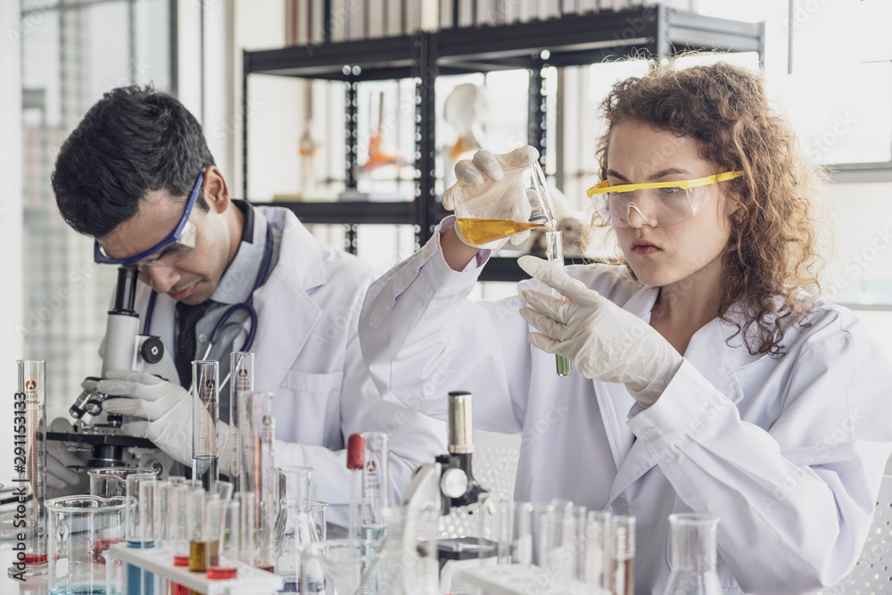 Team of Medical Research Scientist Conducts Experiments in Laboratory with Microscope, Test Tubes, Micropipette and other equipment.
