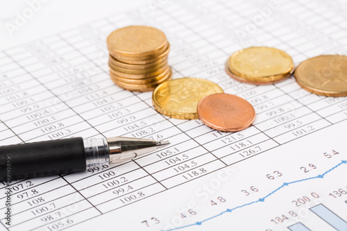 Finance Concept. Financial reports, euro coins, US coin on business chart.