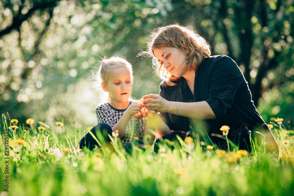 Fototapeta premium Mother and daughter having fun in the park. Happiness and harmony in family life. Beauty nature scene with family outdoor lifestyle. Woman and cheerful little girl