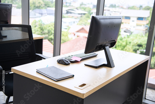 Modern office interior design with table, computer, monitor, note book and big glass window around the room without people