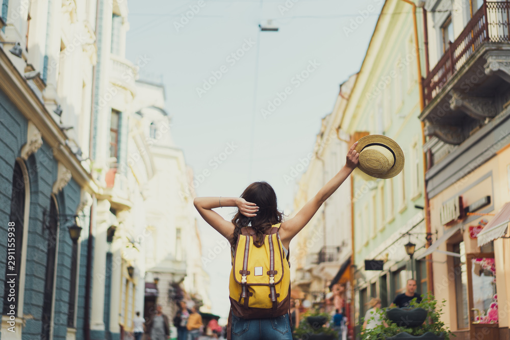 Back view of a young woman traveler with a backpack on her shoulder out ...