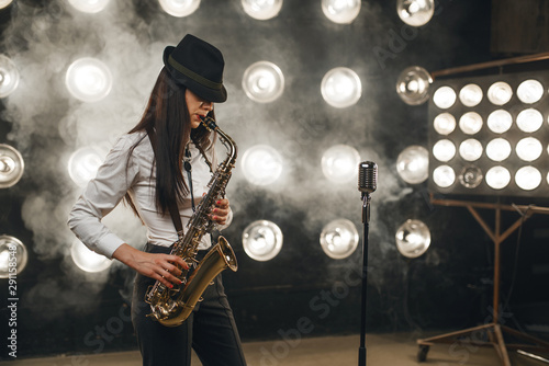 Female jazz musician in hat plays the saxophone