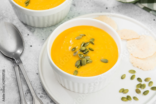 Creamy pumpkin cream soup with seeds. Autumn dish. Light grey background