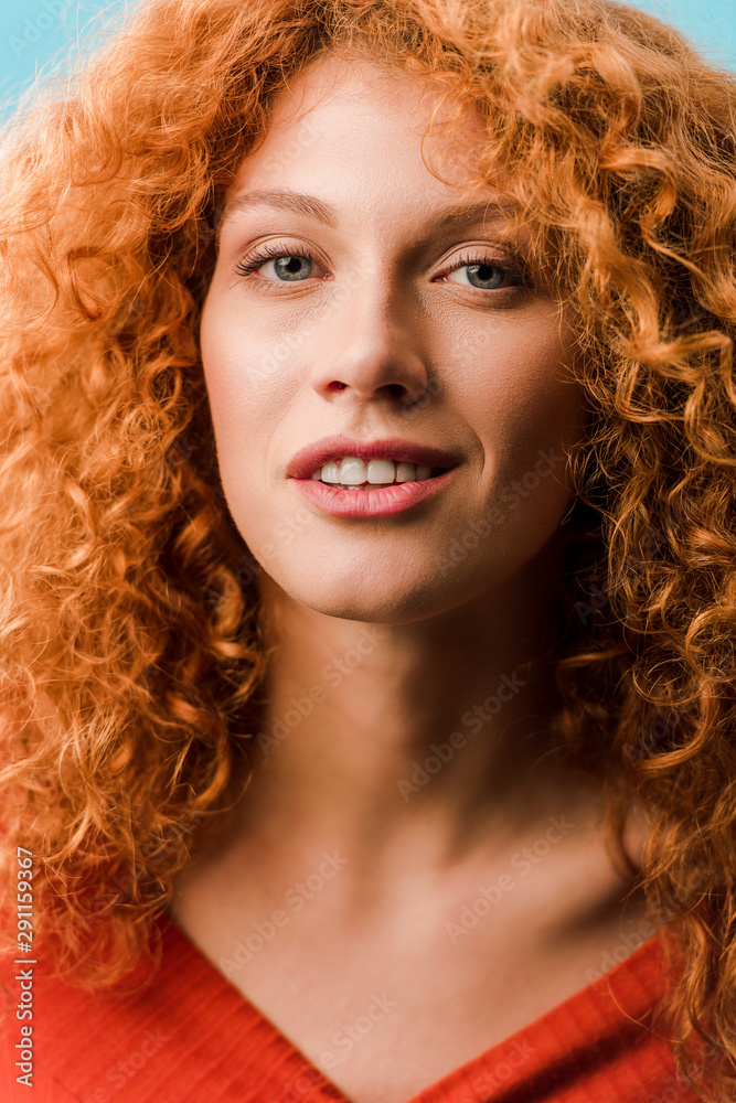 Fototapeta premium portrait of beautiful smiling redhead woman isolated on blue