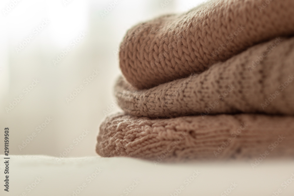 knitted warm pastel sweaters stacked, isolated, close-up