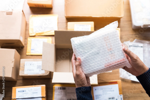 Fotografie Online shopping concepts with male hand packing some product to brown box on another packet for shipping to customer