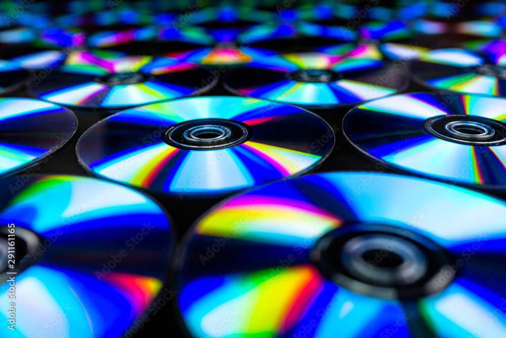 CDs / DVDs lying on a black background with colorful reflections of light. CDs / DVDs lying on a black background with colorful reflections of light.
