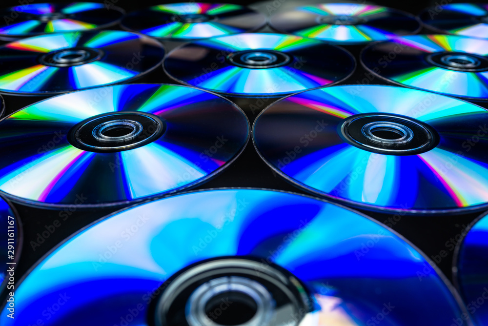 CDs / DVDs lying on a black background with colorful reflections of light. CDs / DVDs lying on a black background with colorful reflections of light.