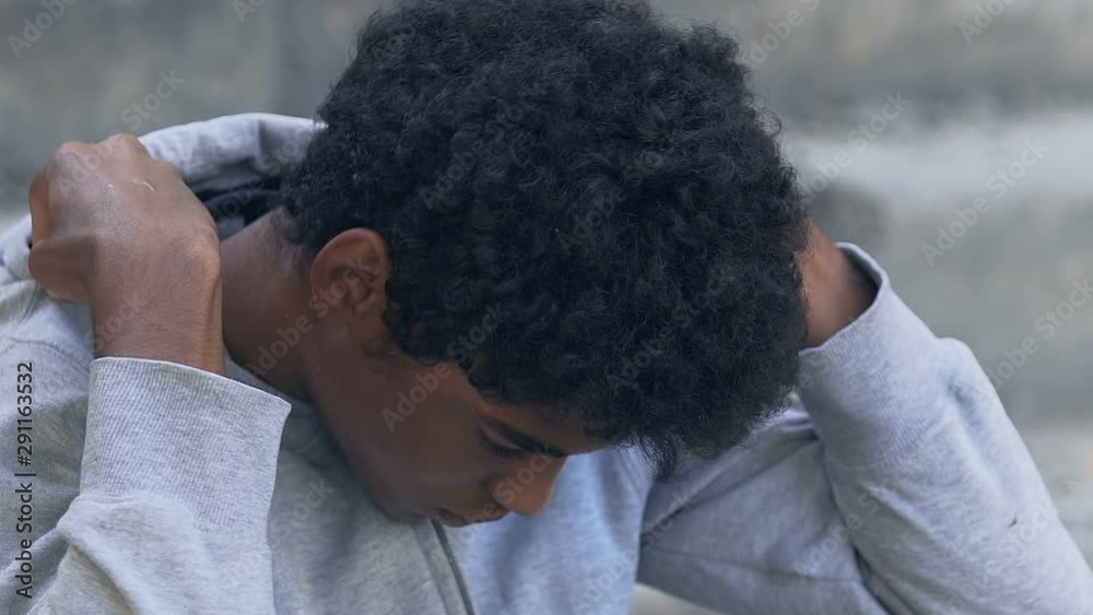 Offended afro-american teen guy wearing hood, thinking about life problems Offended afro-american teen guy wearing hood, thinking about life problems