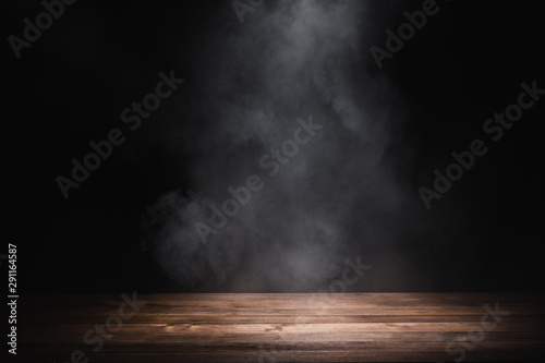 empty wooden table with smoke float up on dark background