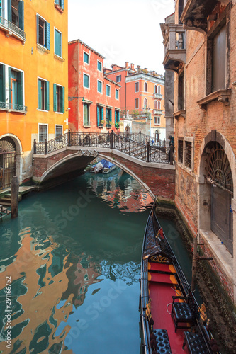 Boats on narrow canal between colorful historic houses in Venice.