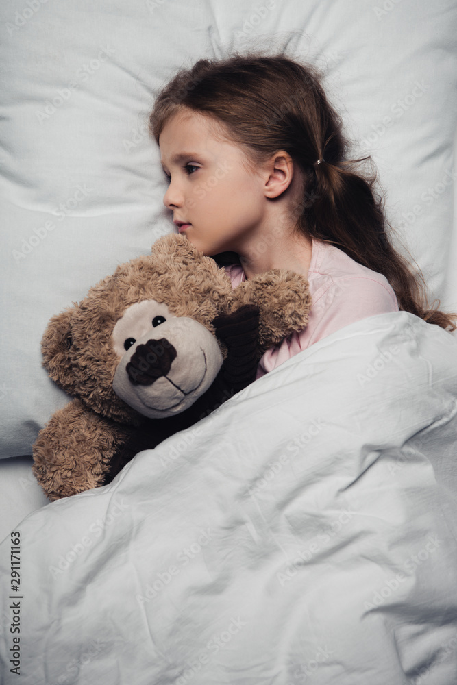 adorable scared child lying in bed with open eyes near teddy bear adorable scared child lying in bed with open eyes near teddy bear