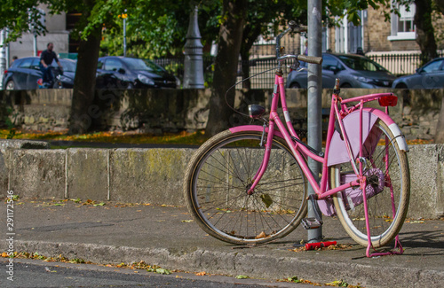 Pink bike bicycle on tree lined street, Grand Canal, Dublin, Ireland. Cyclist and green trees in background on sunny day
