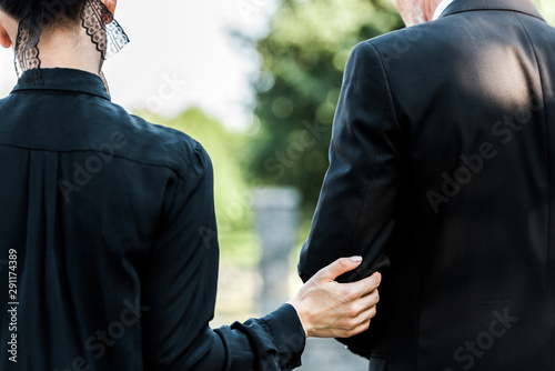 cropped view of woman touching elderly man on funeral