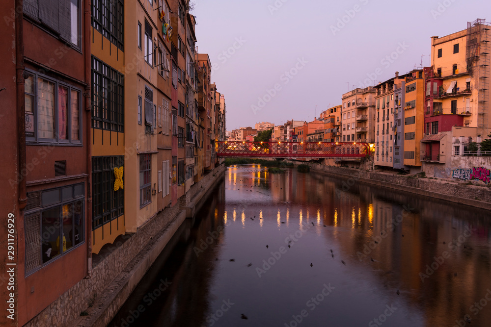 Colorful yellow and orange houses reflected in water river Onyar, in Girona, Catalonia, Spain.