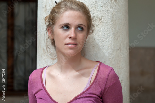 Young blonde girl photographed in the cloister of an old building