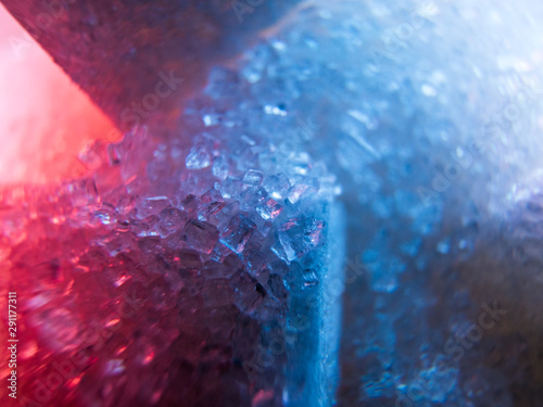 Heap of transparent white sugar crystals with large pieces of sugar in mixed colour light. Macro photo photo