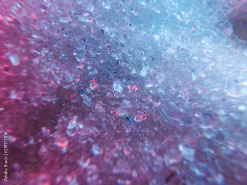 Heap of transparent white sugar crystals with large pieces of sugar in mixed colour light. Macro photo photo