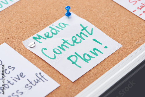 paper card with media content plan lettering pinned on cork office board photo