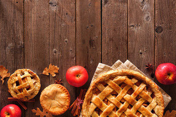 Homemade autumn apple pie bottom border. Above view table scene over a rustic wood background with copy space.