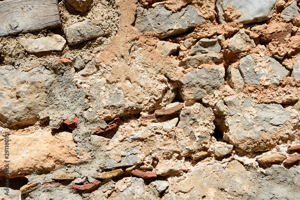 Fototapeta premium Fragment of an ancient wall illuminated by the bright sun close-up. Stone wall background.