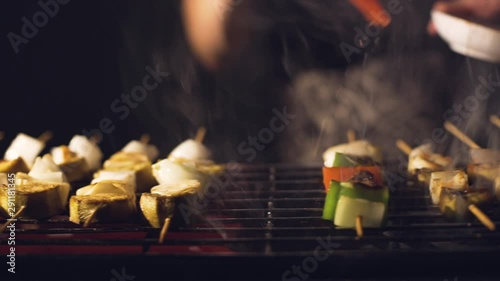 Brushing skewers with oil.