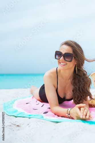 40 year old woman looking into distance and sun bathing on towel