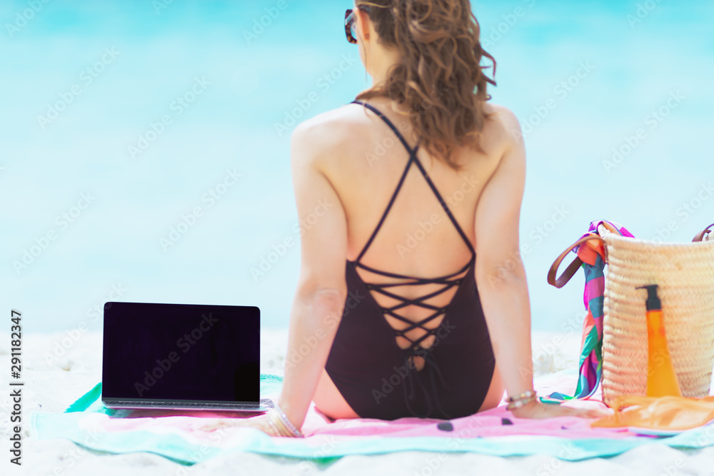 40 year old woman sitting near laptop on round watermelon towel