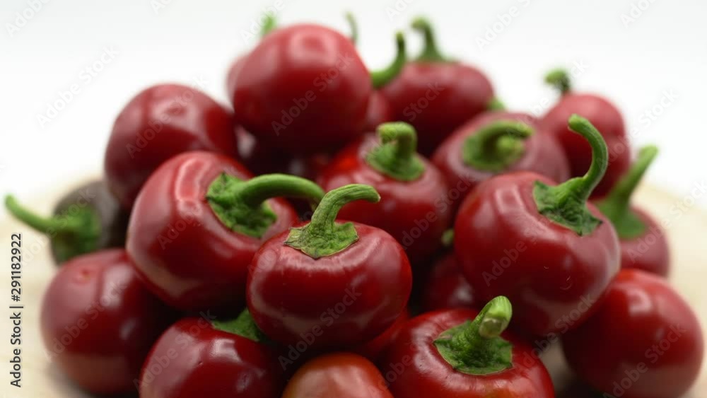 Close-up of rotating red hot chili peppers on plate. Fresh spices ingredients on white background. Red hot chili peppers and fiery emotions. Healthy eating concept Close-up of rotating red hot chili peppers on plate. Fresh spices ingredients on white background. Red hot chili peppers and fiery emotions. Healthy eating concept