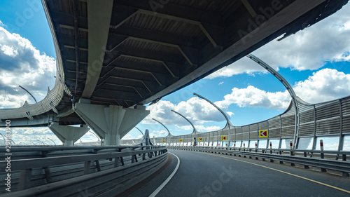 Expressway on the background of blue sky with clouds. Transport infrastructure. The highways are located on two levels. Empty Expressway. Road junction. Road safety.