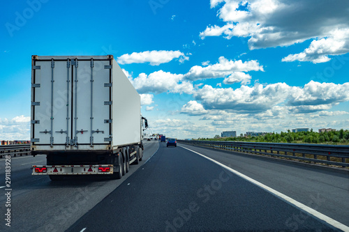 Traffic on the road. Truck rides on the highway. The transport company offers services in a cargo transportation. Sale of freight transport. Refrigerator on the highway.