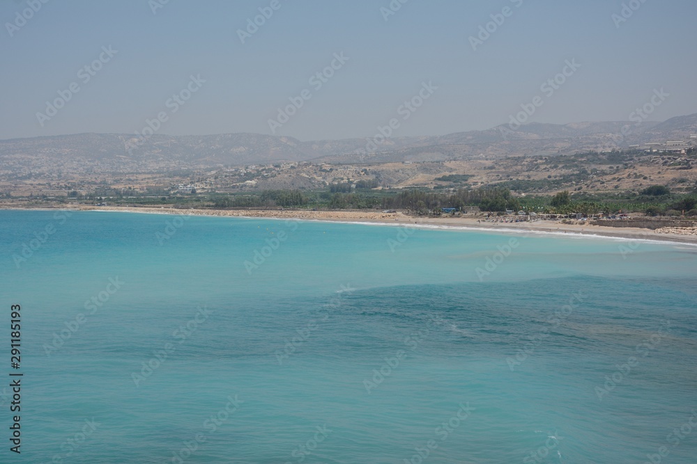 turquoise water and a beach against mountains in a haze turquoise water and a beach against mountains in a haze