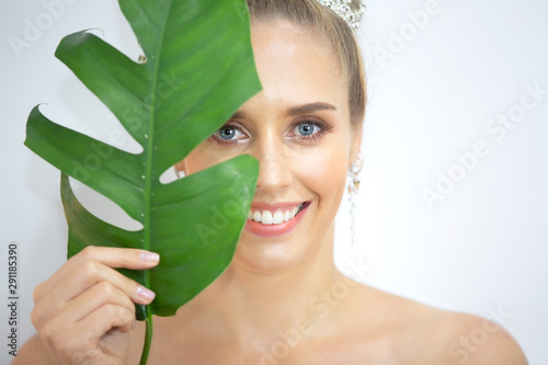 Portrait of young and beautiful woman with perfect smooth skin in tropical leaves. Concept of natural cosmetics and skincare with Clean Fresh