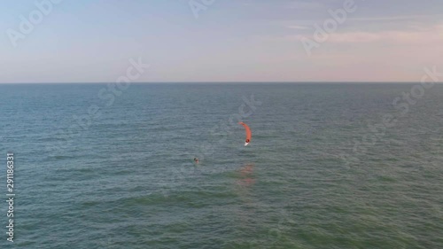 Aerial view of kitesurfer gliding and jumping across ocean