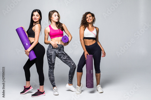 Group of three female athletes give each other high five after a good training session in the studio. Attractive sporty fitness girl smiling indoor.