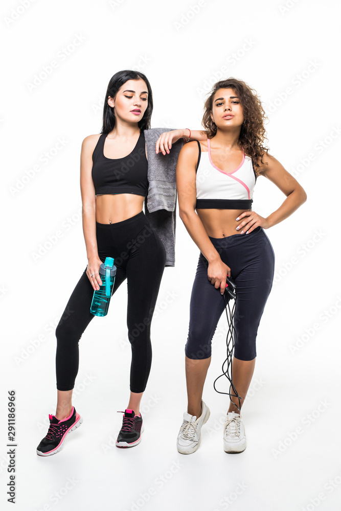 Portrait of two fitness women standing isolated on white background